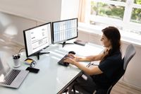 Frau mit 2 Bildschirmen arbeitet am PC
